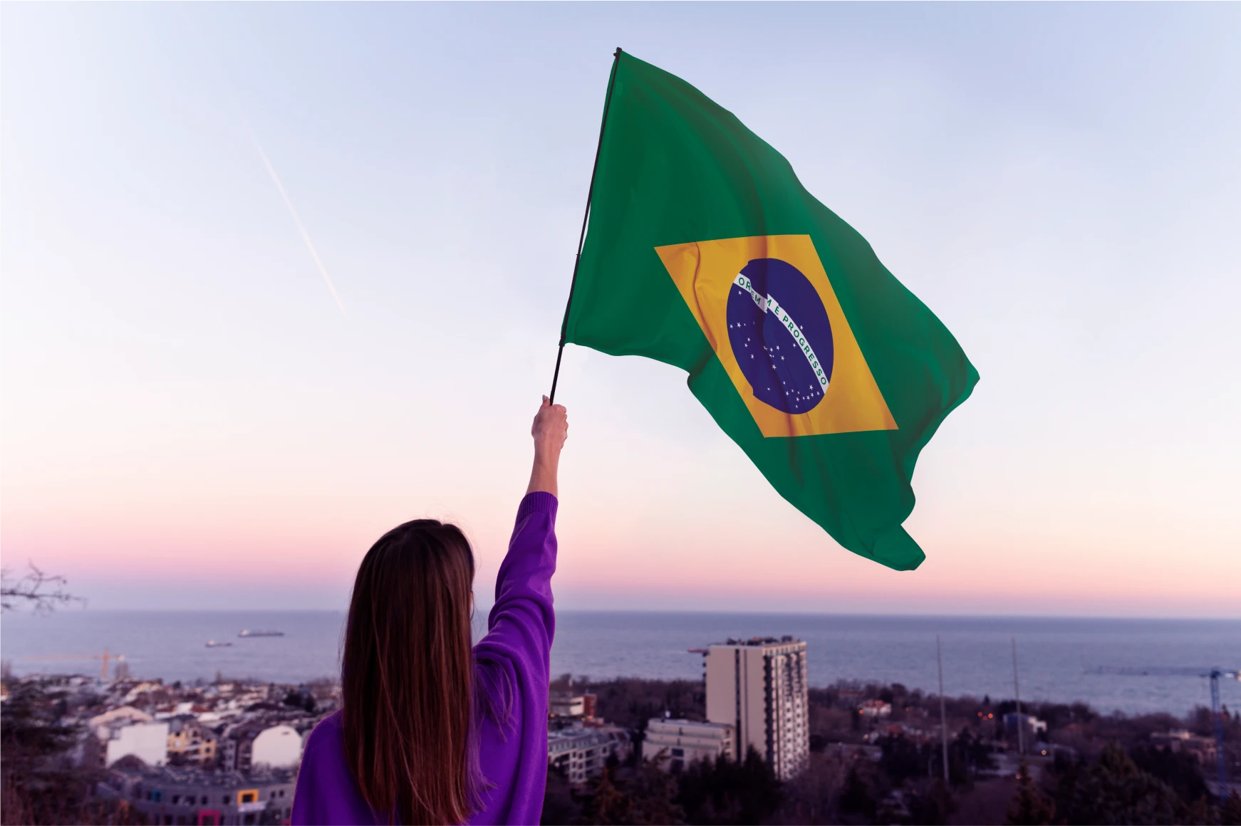 Mulher de costas segurando a bandeira do Brasil, representando presença nacional